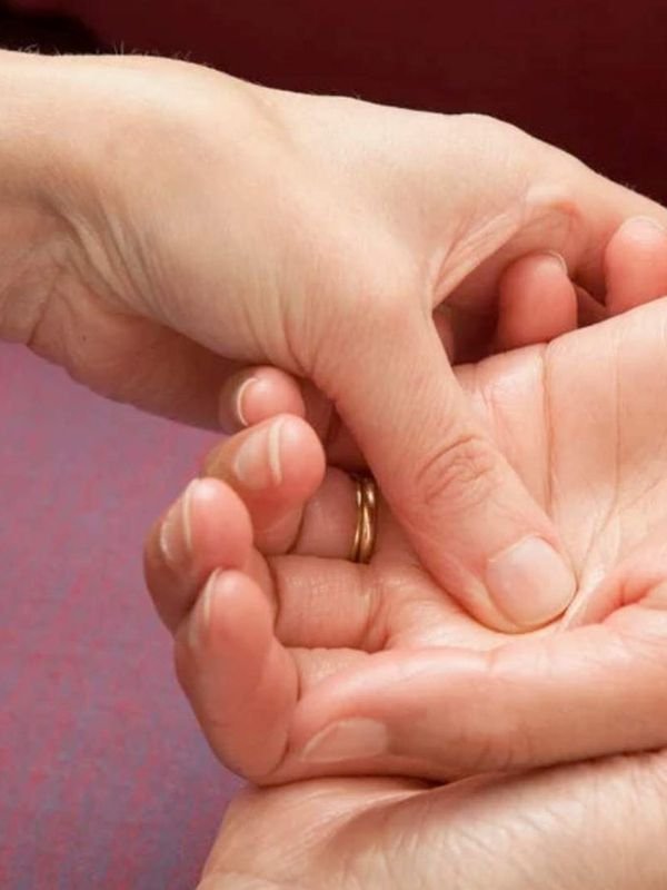 Thumb pressure on a reflex point in the palm during reflexology