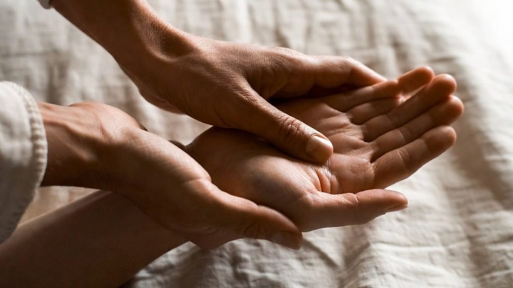 Thumb pressure on a reflex point in the palm during hand reflexology
