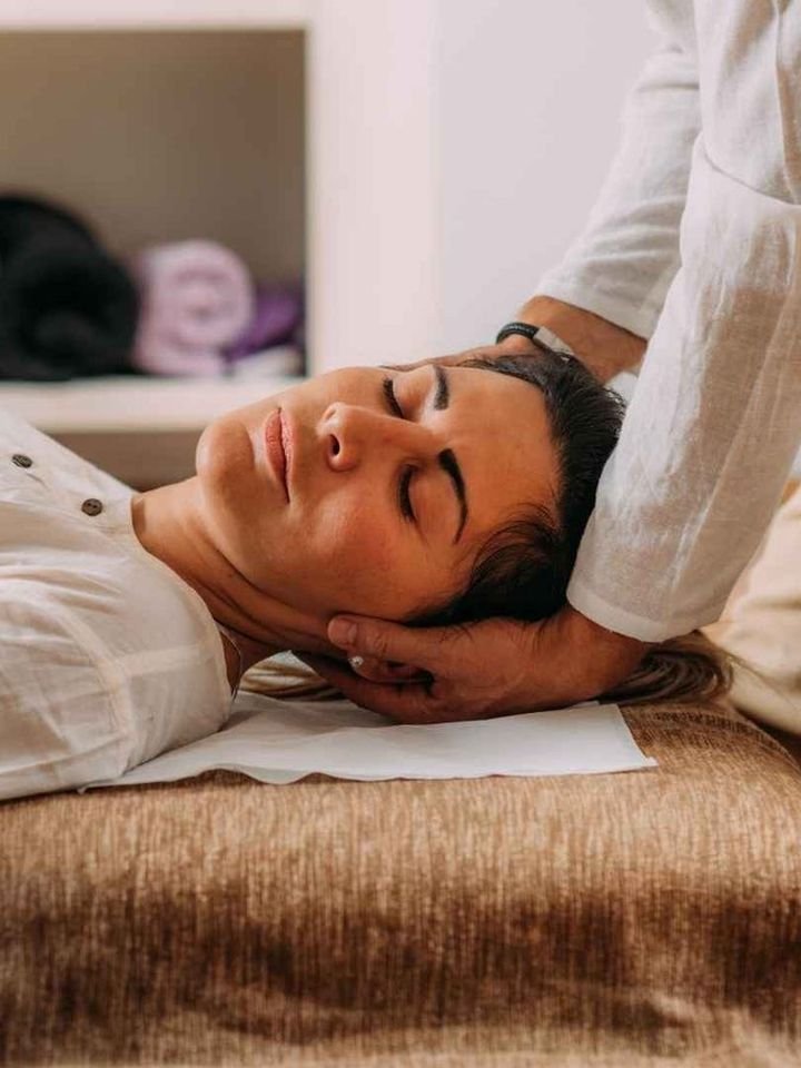 A client resting as Sunil’s hands cradle her head during a Shiatsu session at home in Mumbai