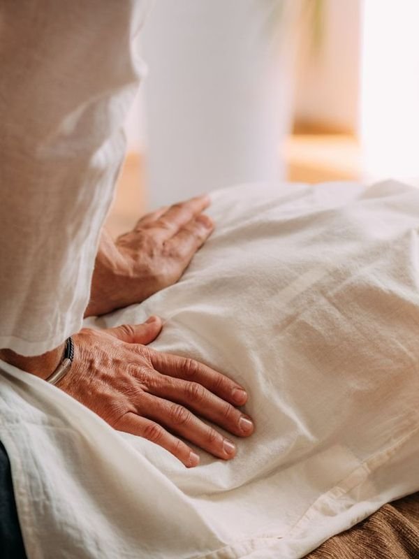 Hands applying Shiatsu pressure to a client’s abdomen